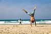 man doet handstand op strand