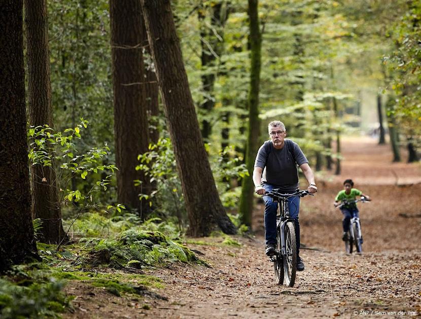 man met kind fietsen in bos